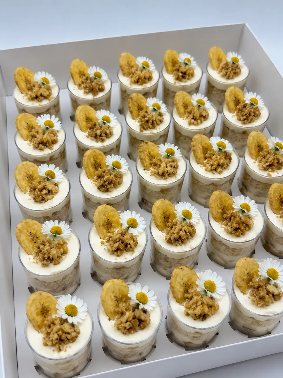Banana walnut mini dessert shots topped with banana chips, chopped walnuts, and edible flowers