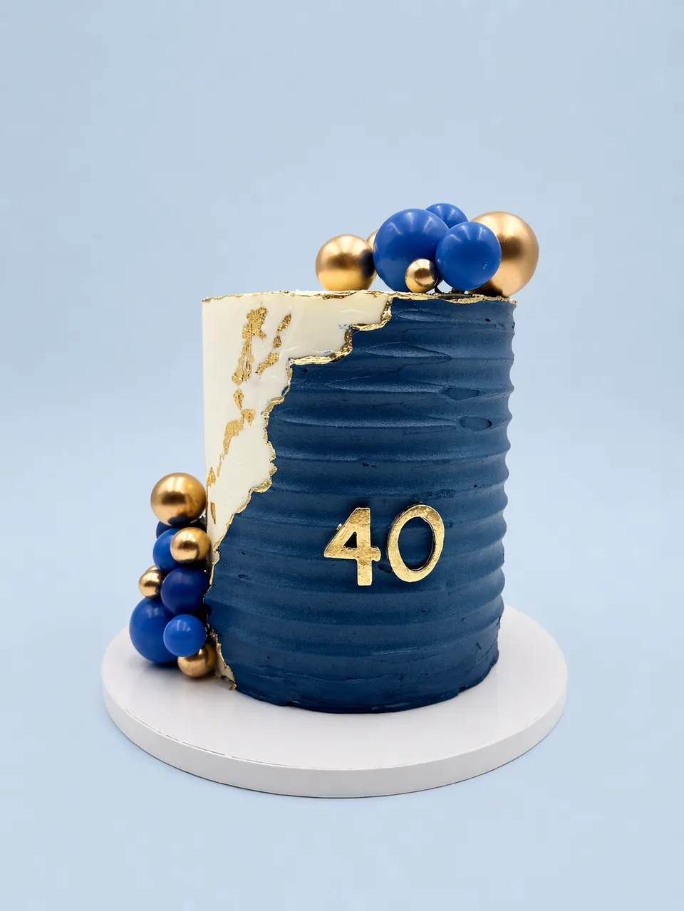 Blue and gold 40th birthday cake with modern buttercream texture and balloon accents