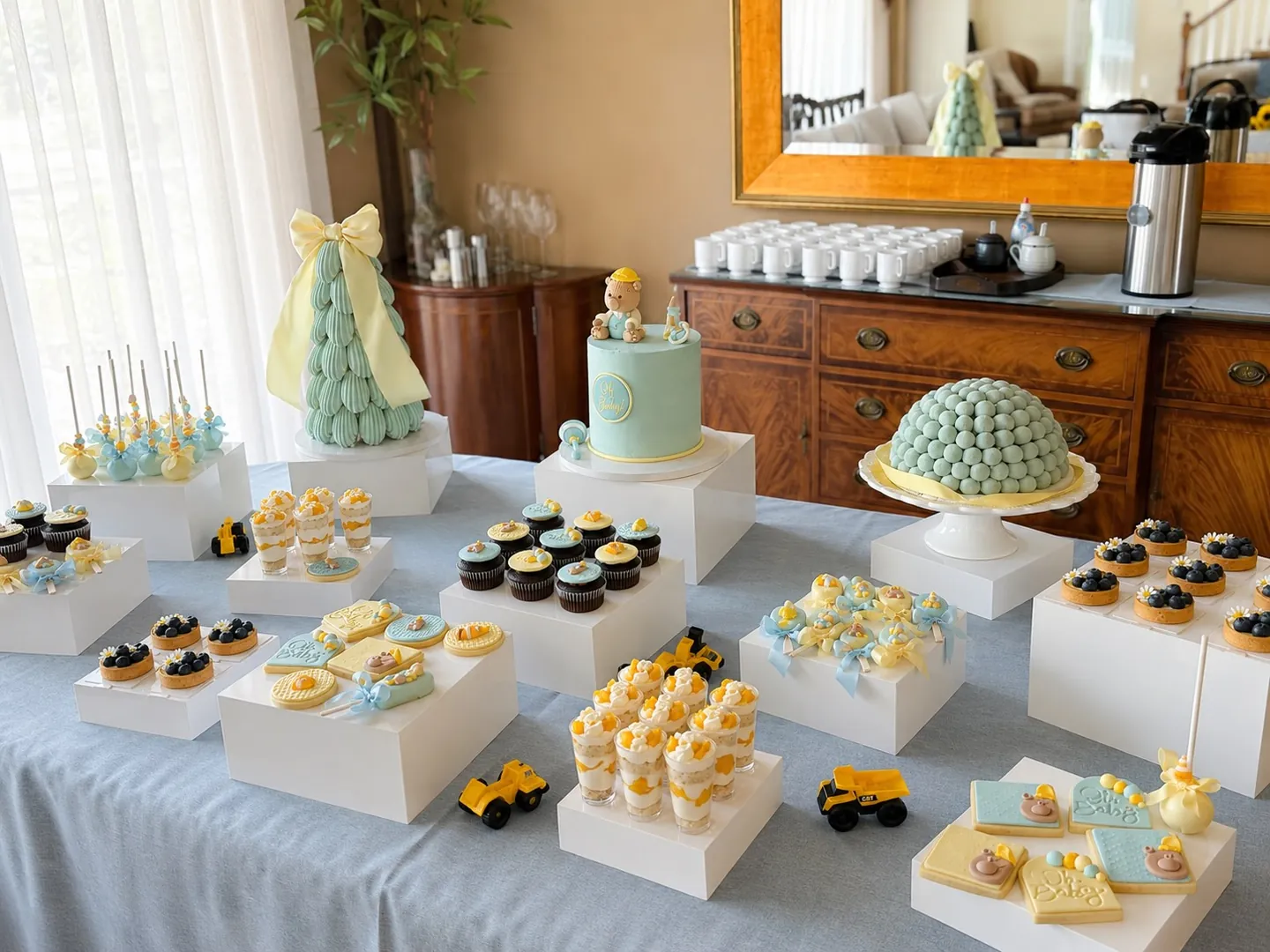 Blue and yellow baby shower sweet table with cake, mini desserts, and cookies