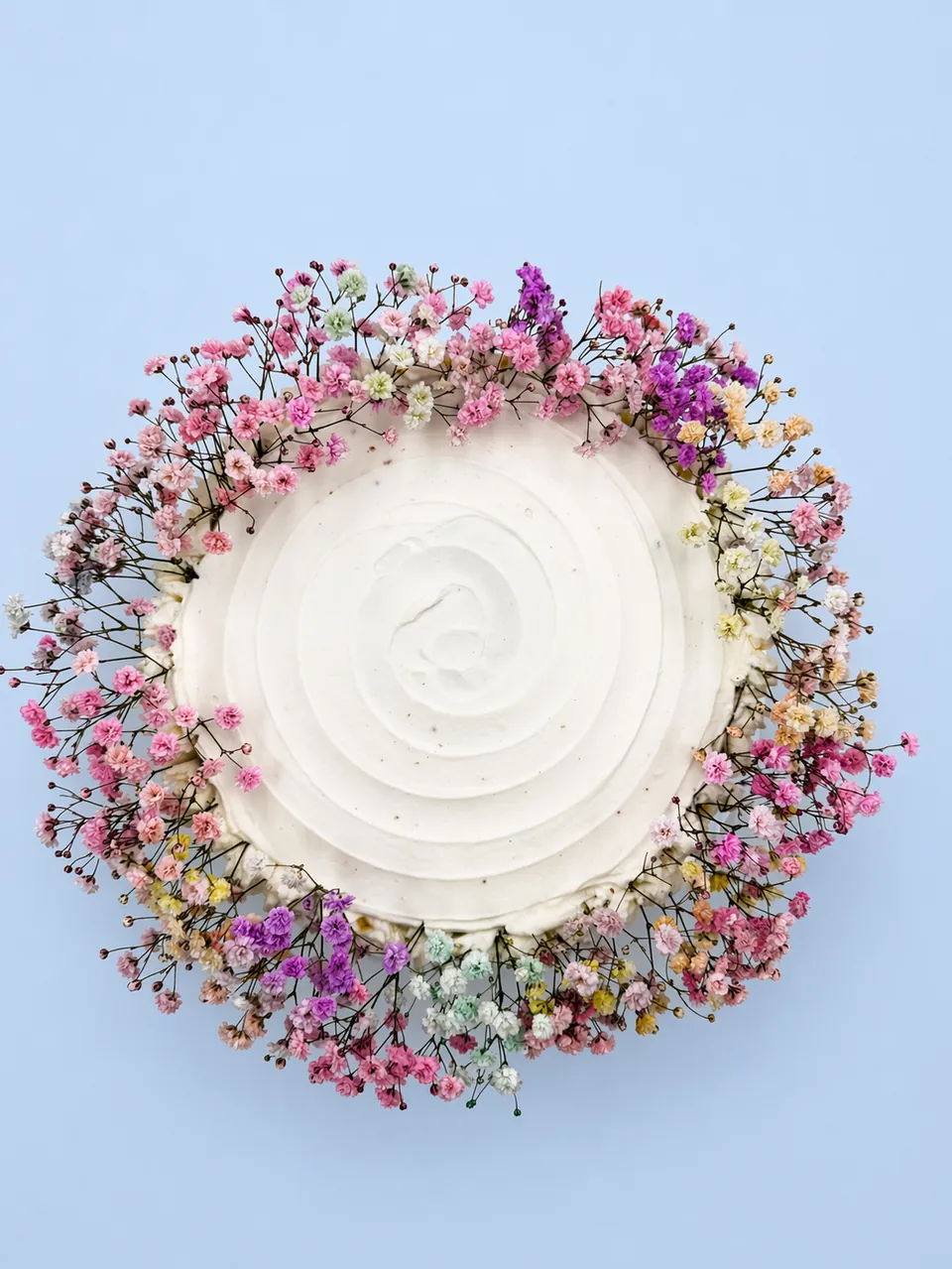 Round buttercream celebration cake framed with a colorful floral wreath