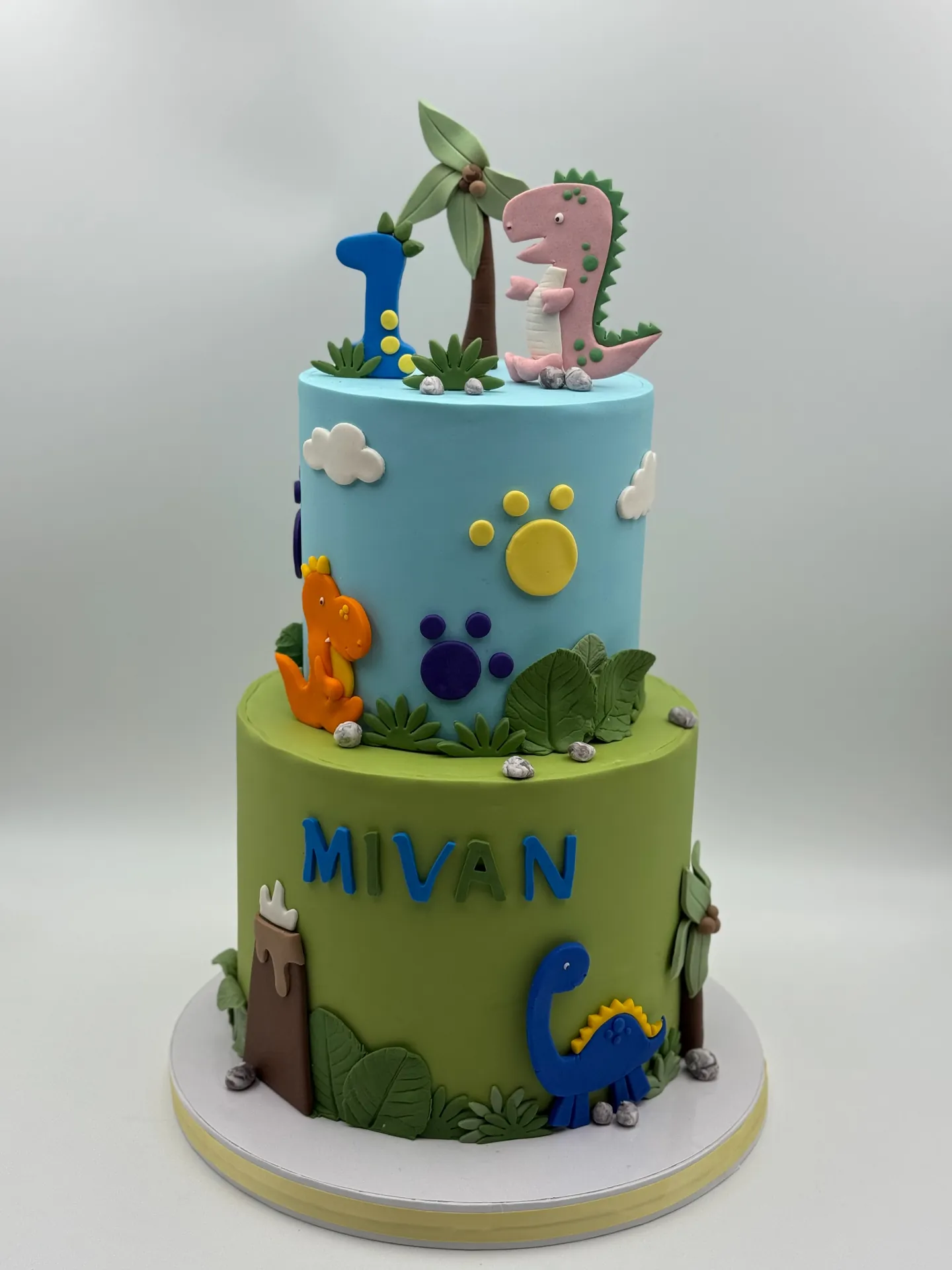 Colorful two-tier dinosaur first birthday cake with handcrafted decorations