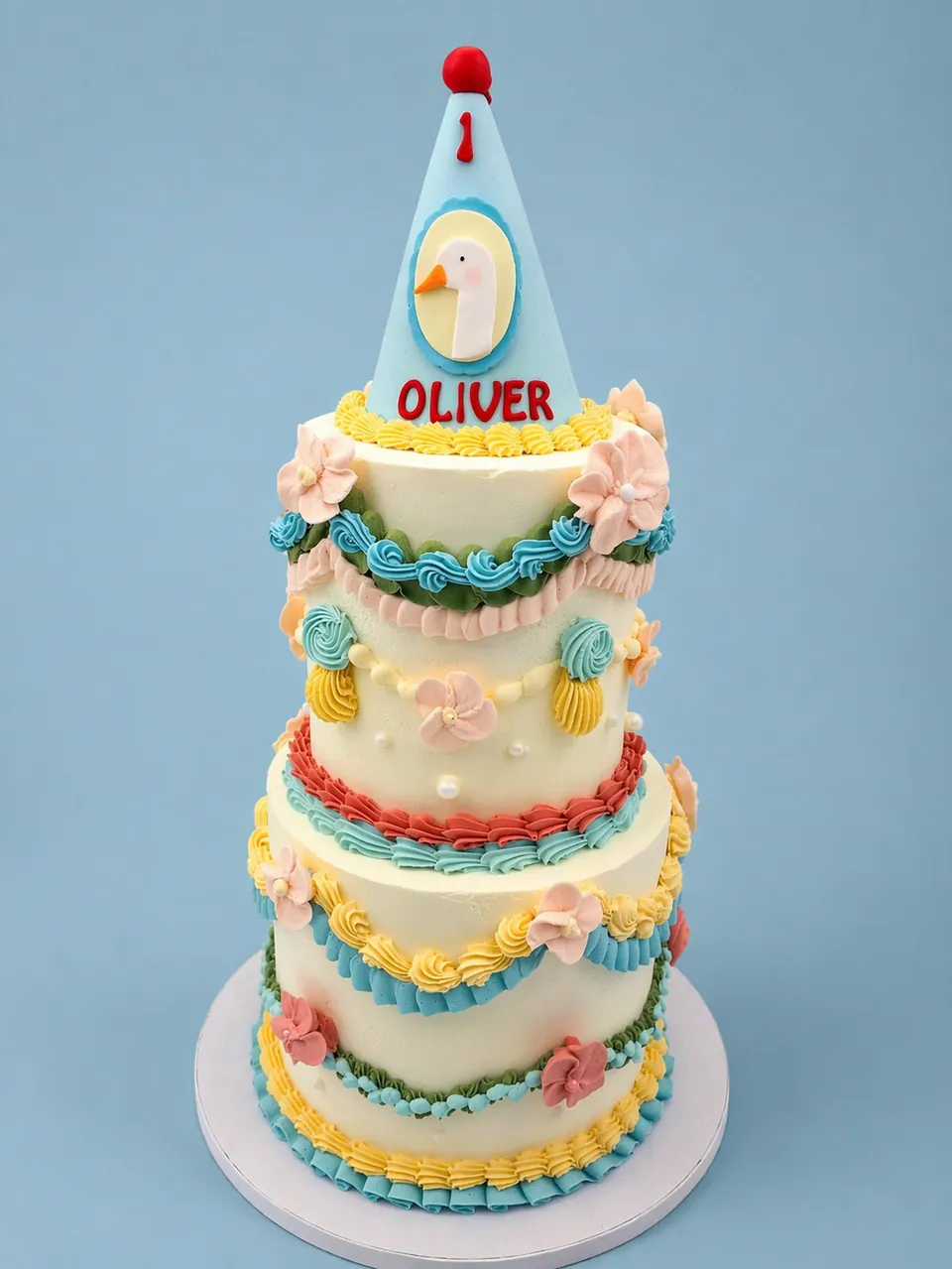 Vintage-style first birthday cake with goose topper and pastel piping