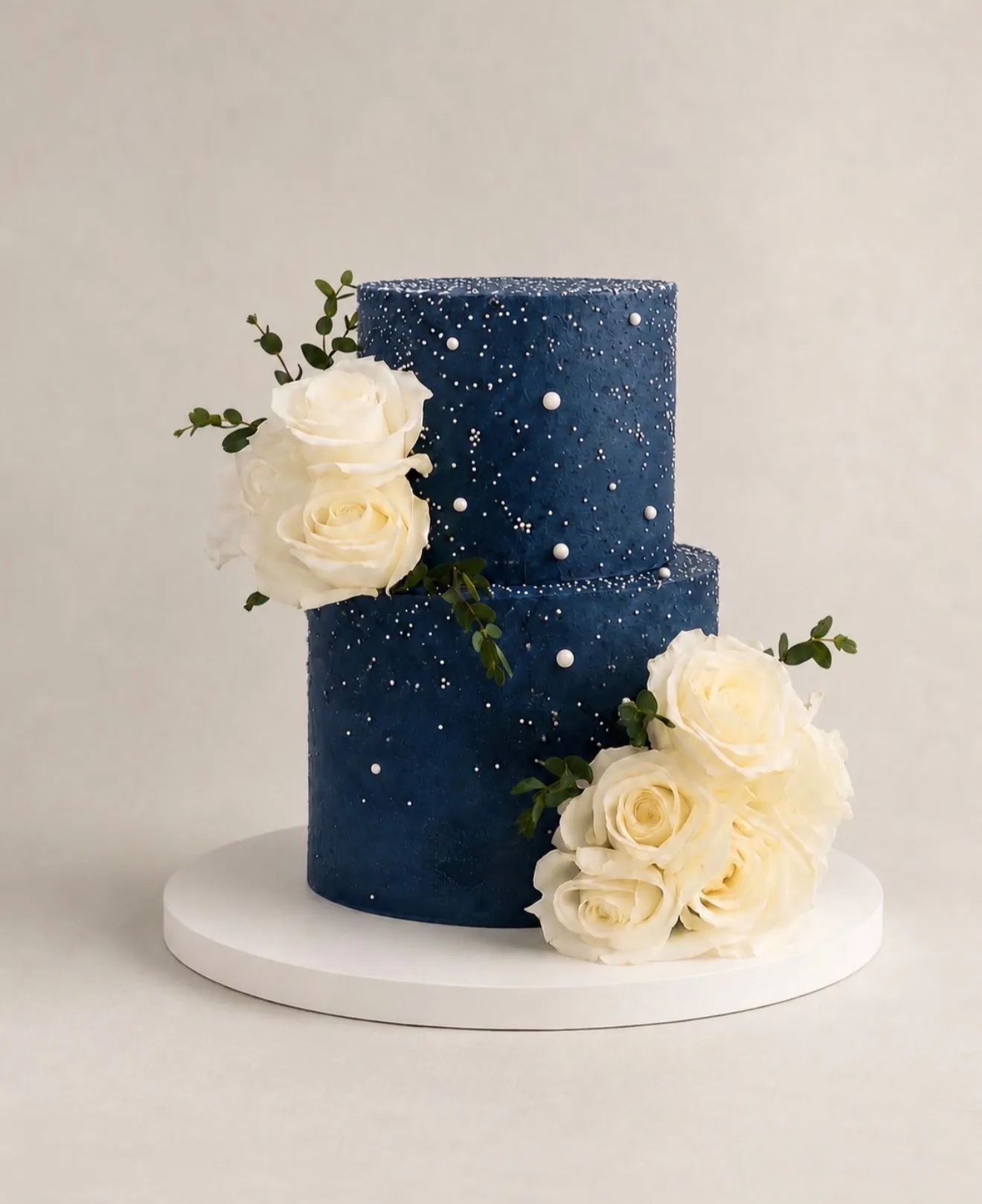 Navy blue two-tier wedding cake with white roses and pearl accents
