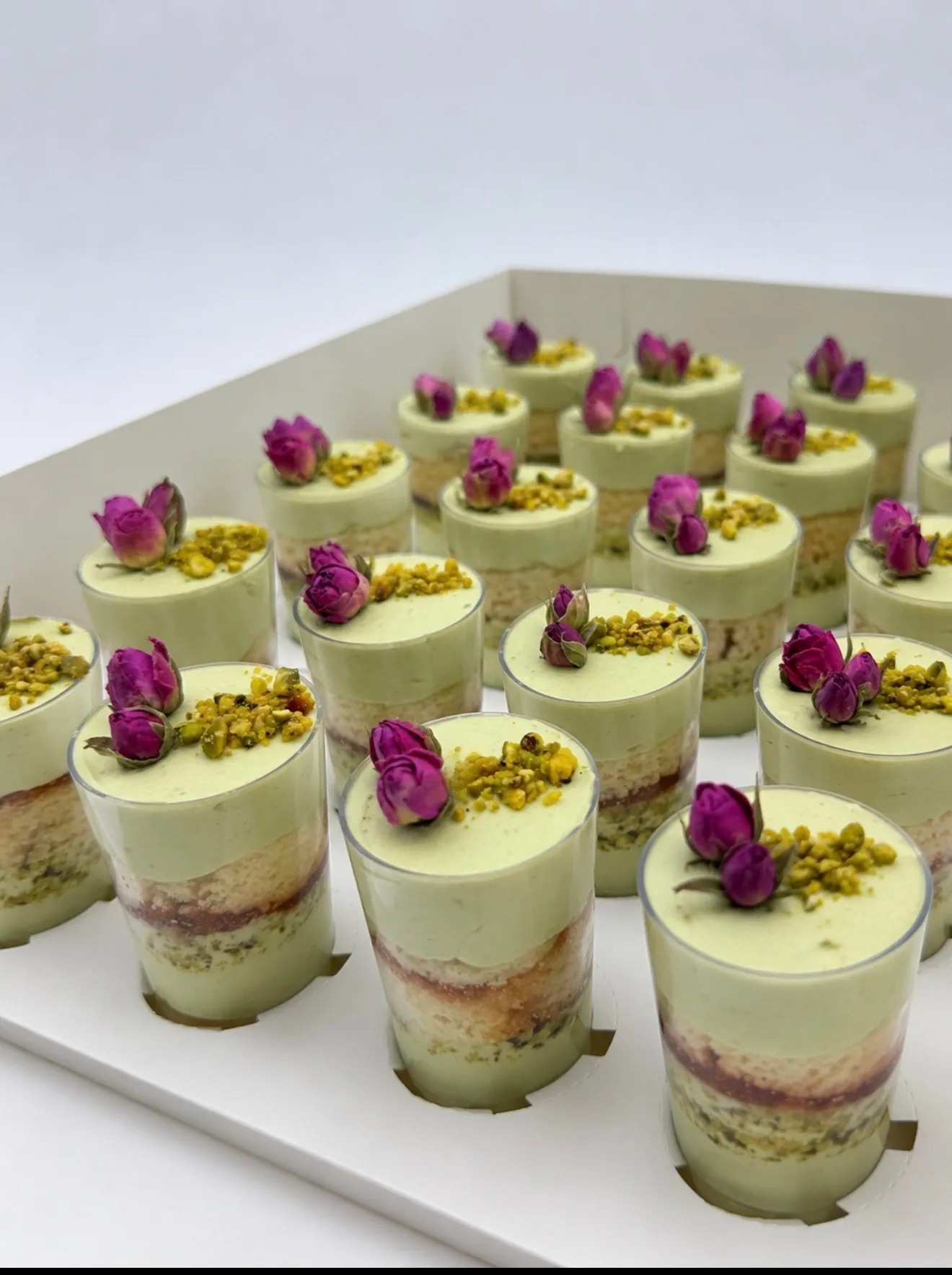 Pistachio mini dessert shots topped with chopped pistachios and dried rosebuds