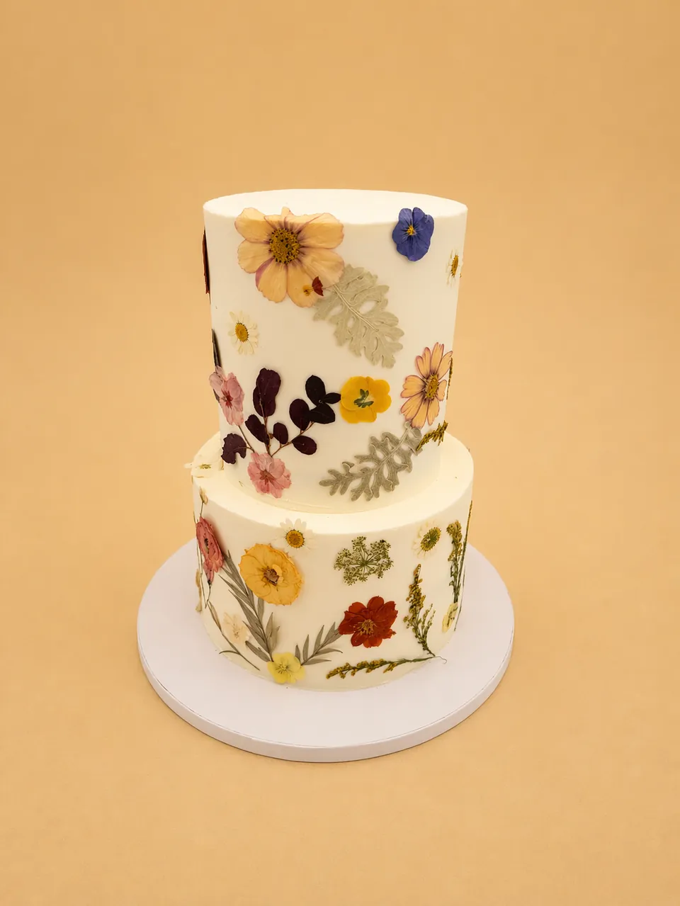 Two-tier pressed flower wedding cake with botanical floral design