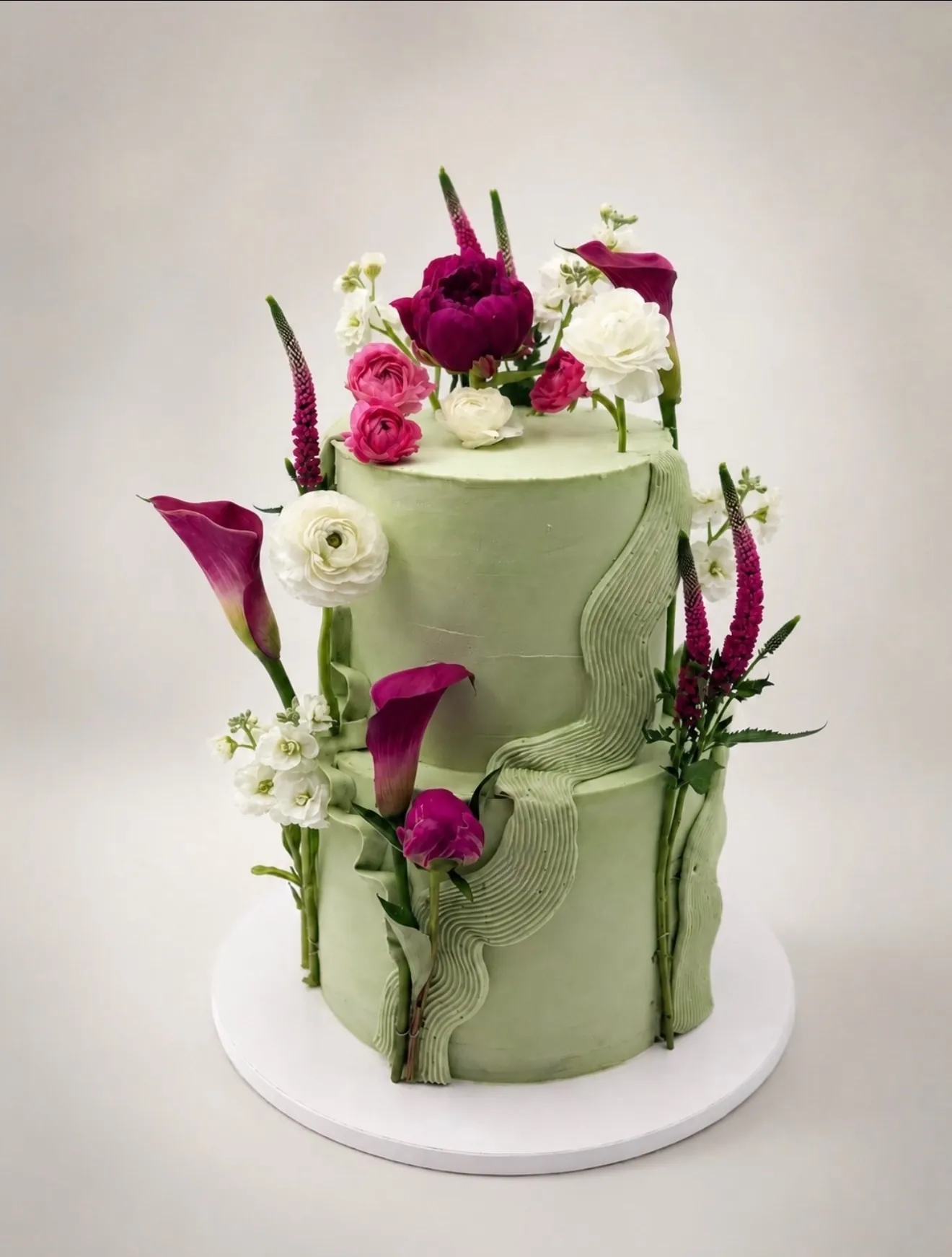 Sage green two-tier floral custom cake with magenta and white fresh flowers