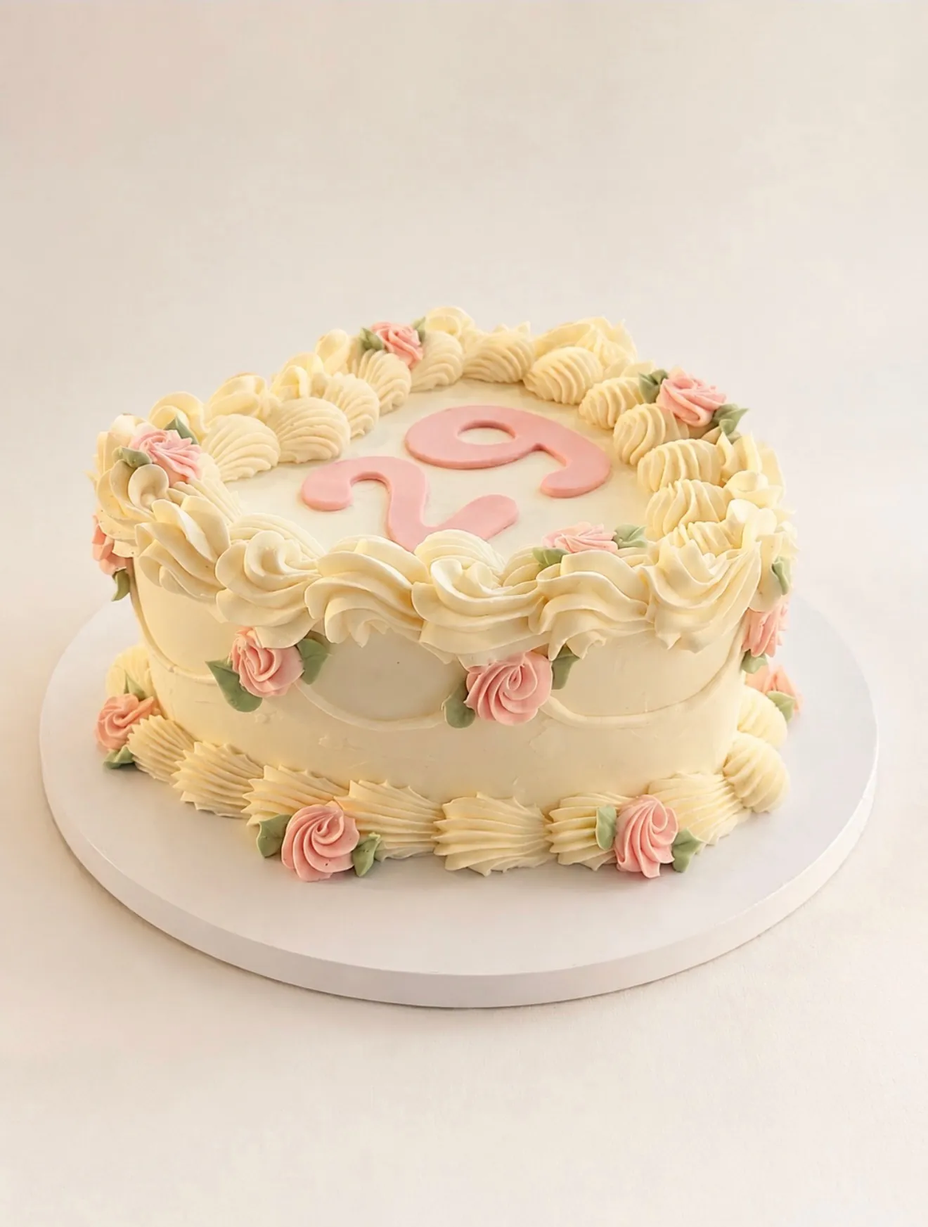 Vintage cream birthday cake with pink roses, piped buttercream border, and pink 25 topper