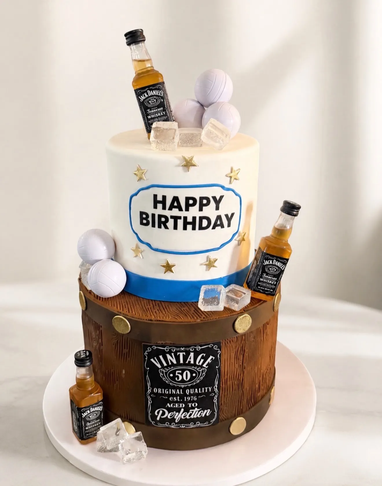 Whiskey-themed 50th birthday cake with mini bottles, ice cubes, and vintage label
