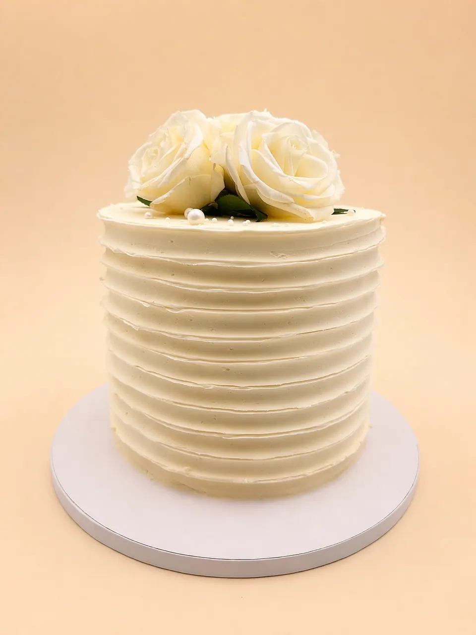 White buttercream rose cake with textured horizontal frosting and pearl accents